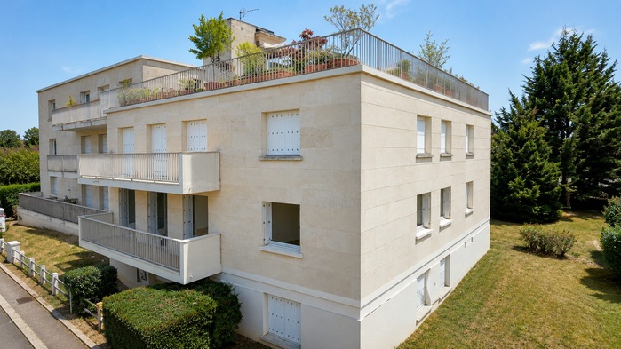 L'immeuble vu de trois quarts, entouré d'arbres, à Margency