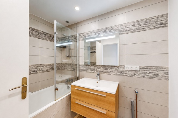 La salle de bains rénovée, avec sa baignoire et son meuble vasque